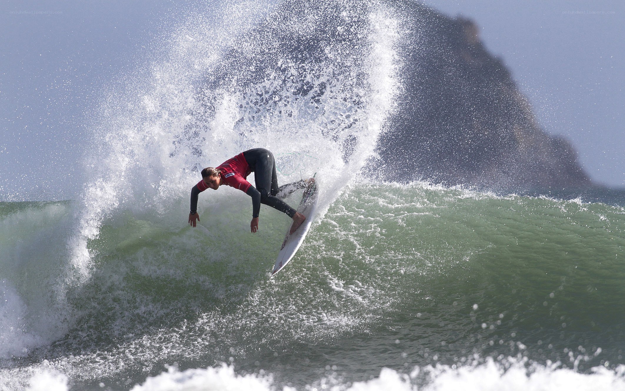 Surfer riding wave in red wetsuit