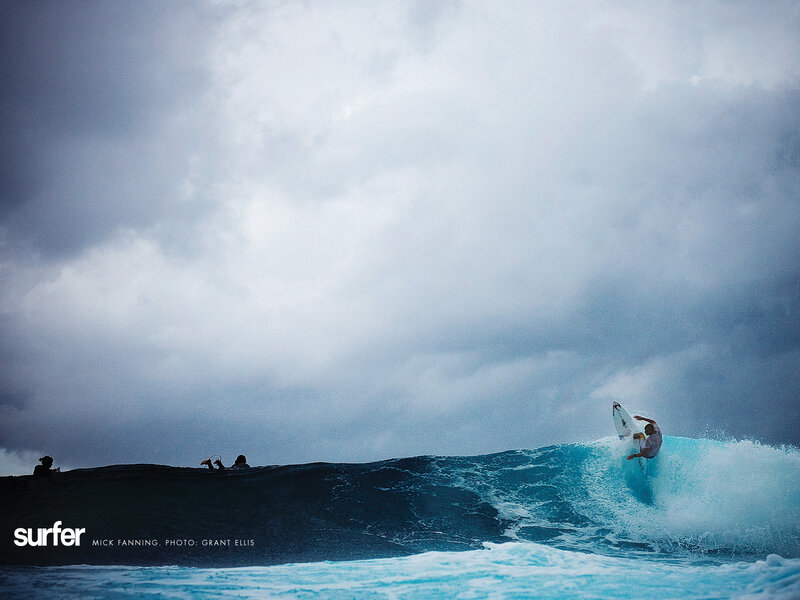 Surfer riding wave in stormy sky