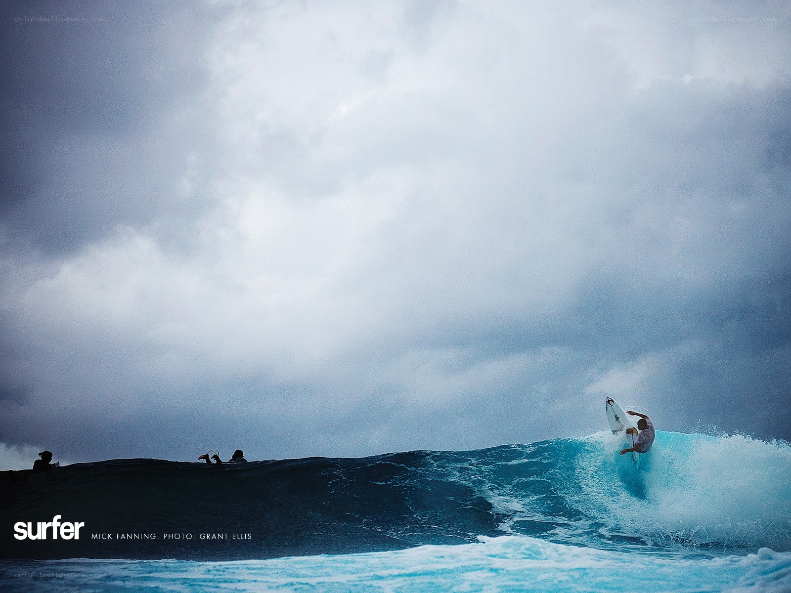 Surfer riding wave in stormy sky