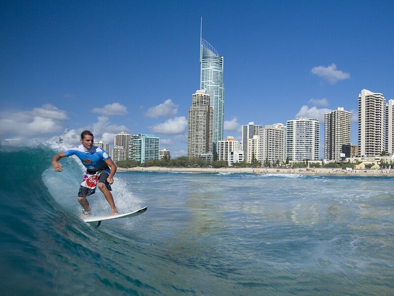 Surfer riding wave near city