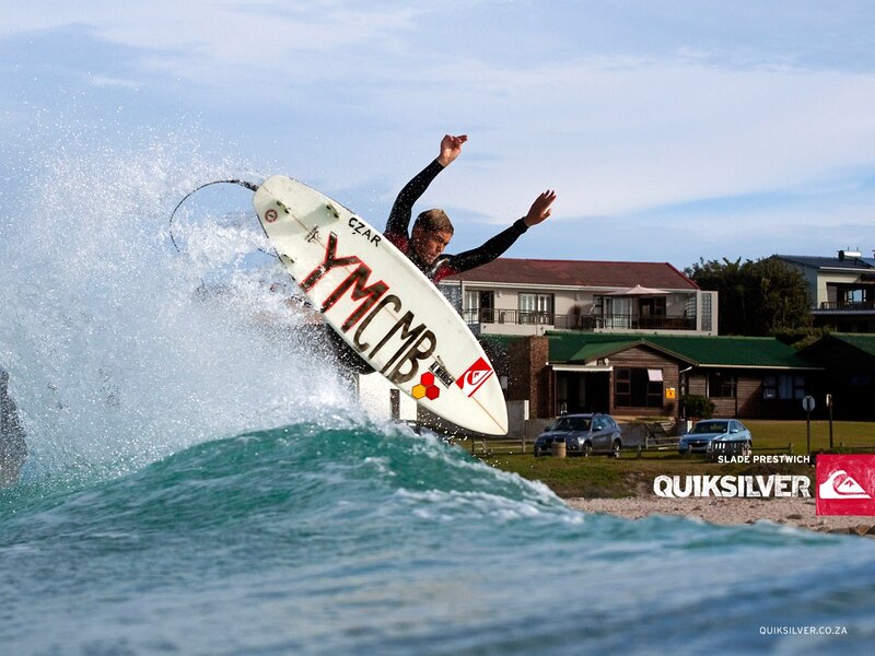 surfer riding wave near houses