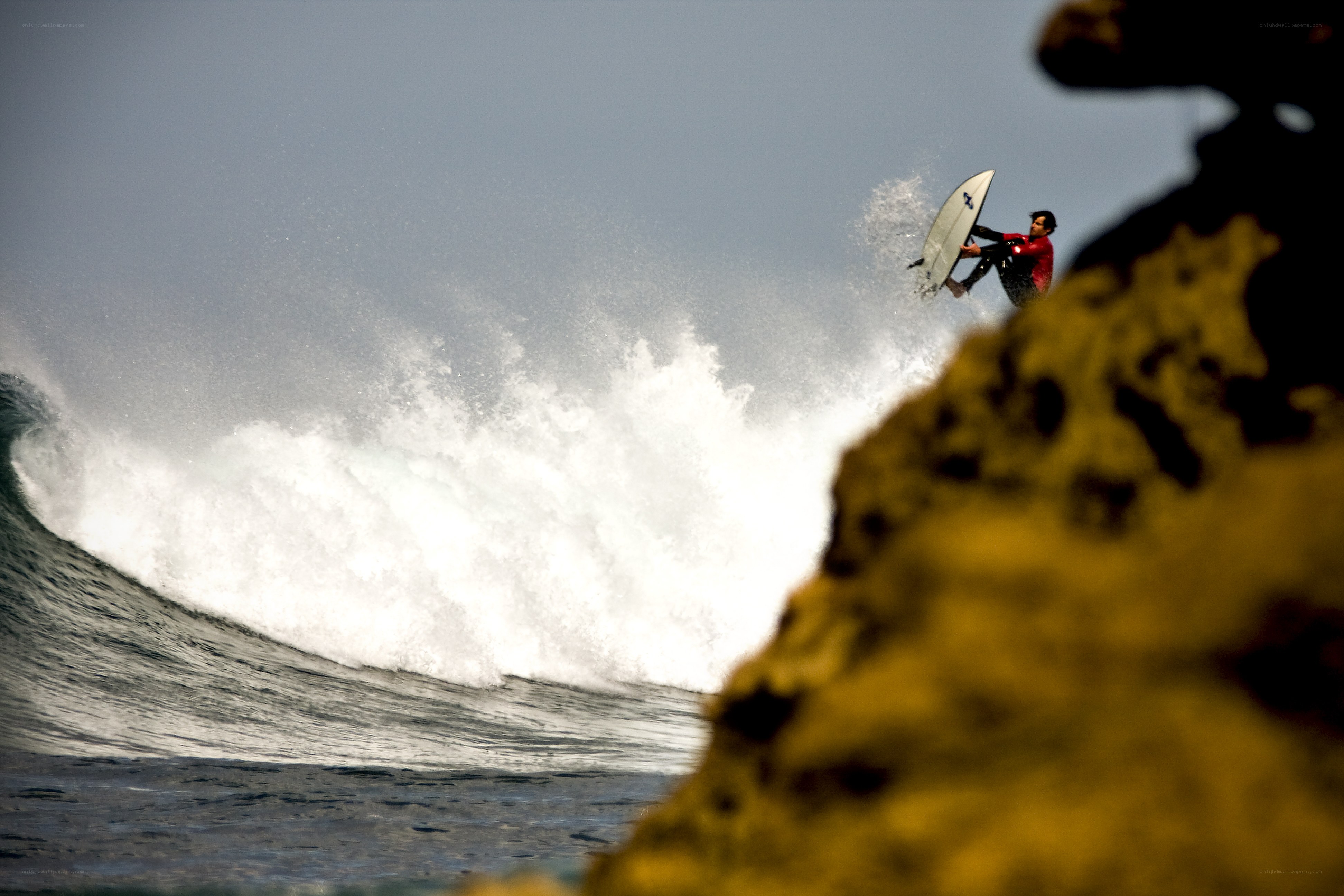Surfer riding wave near rocks