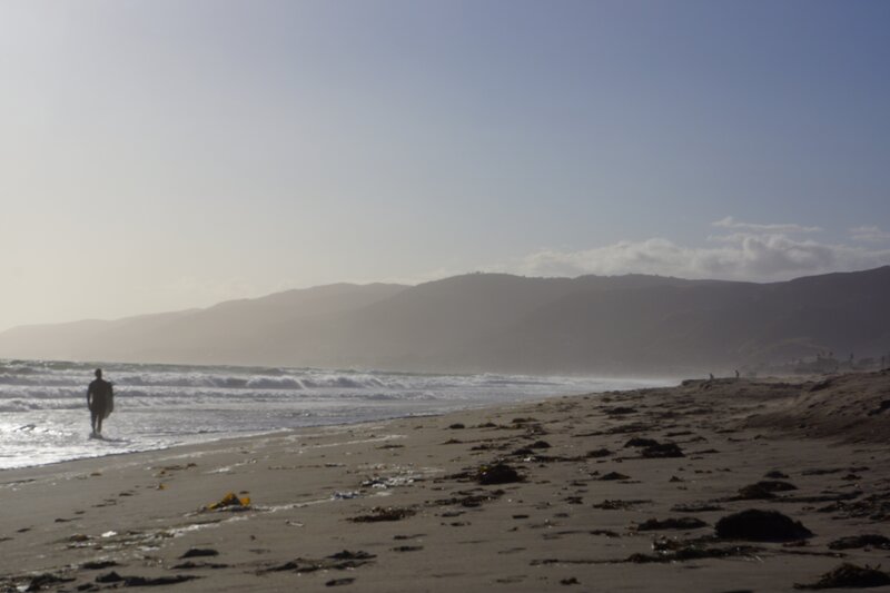 surfer walks along beach