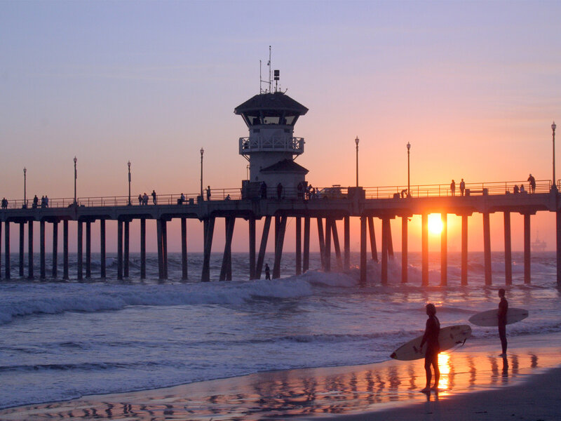 Surfers at sunset by the pier