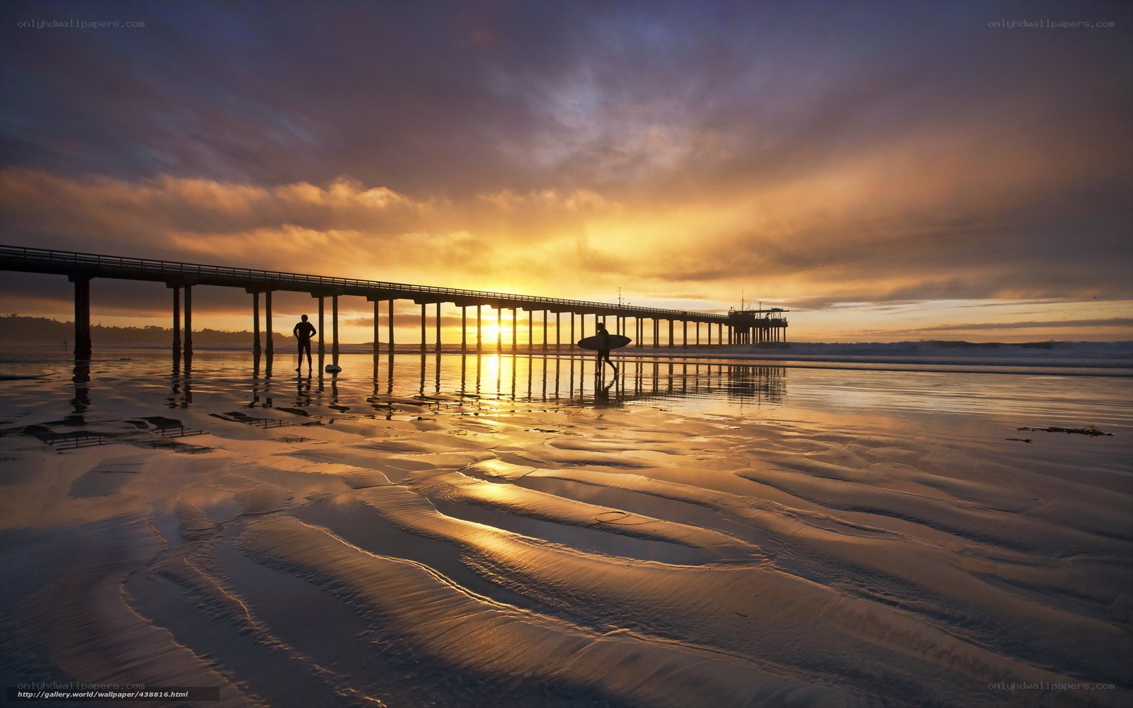 Surfers at sunset by the pier