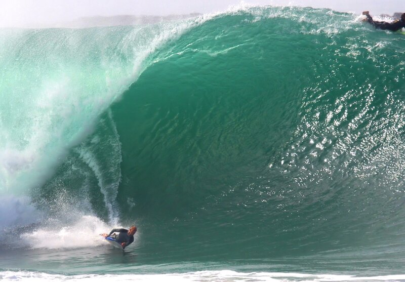 Surfers riding large wave