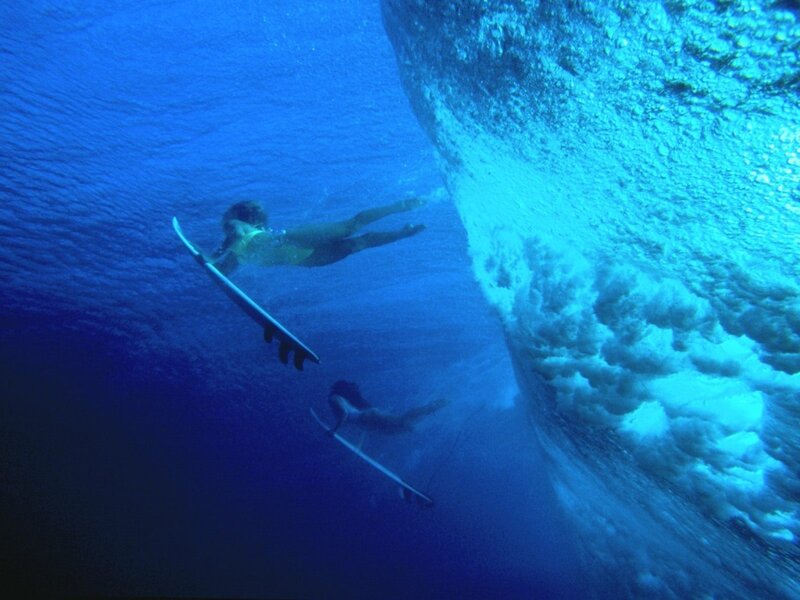 Surfers under a wave