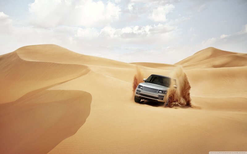 SUV driving through desert dunes