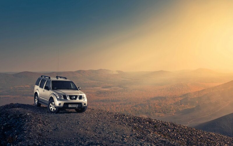 SUV on mountain peak at sunset