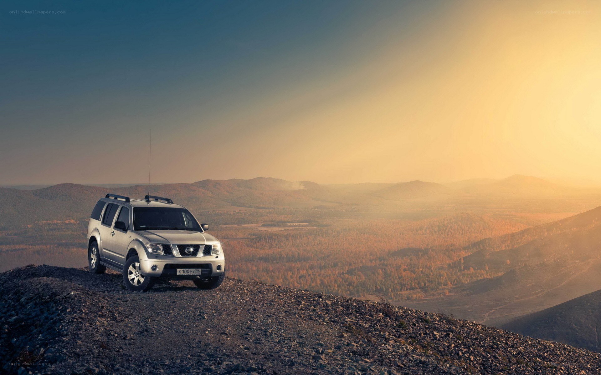 SUV on mountain peak at sunset