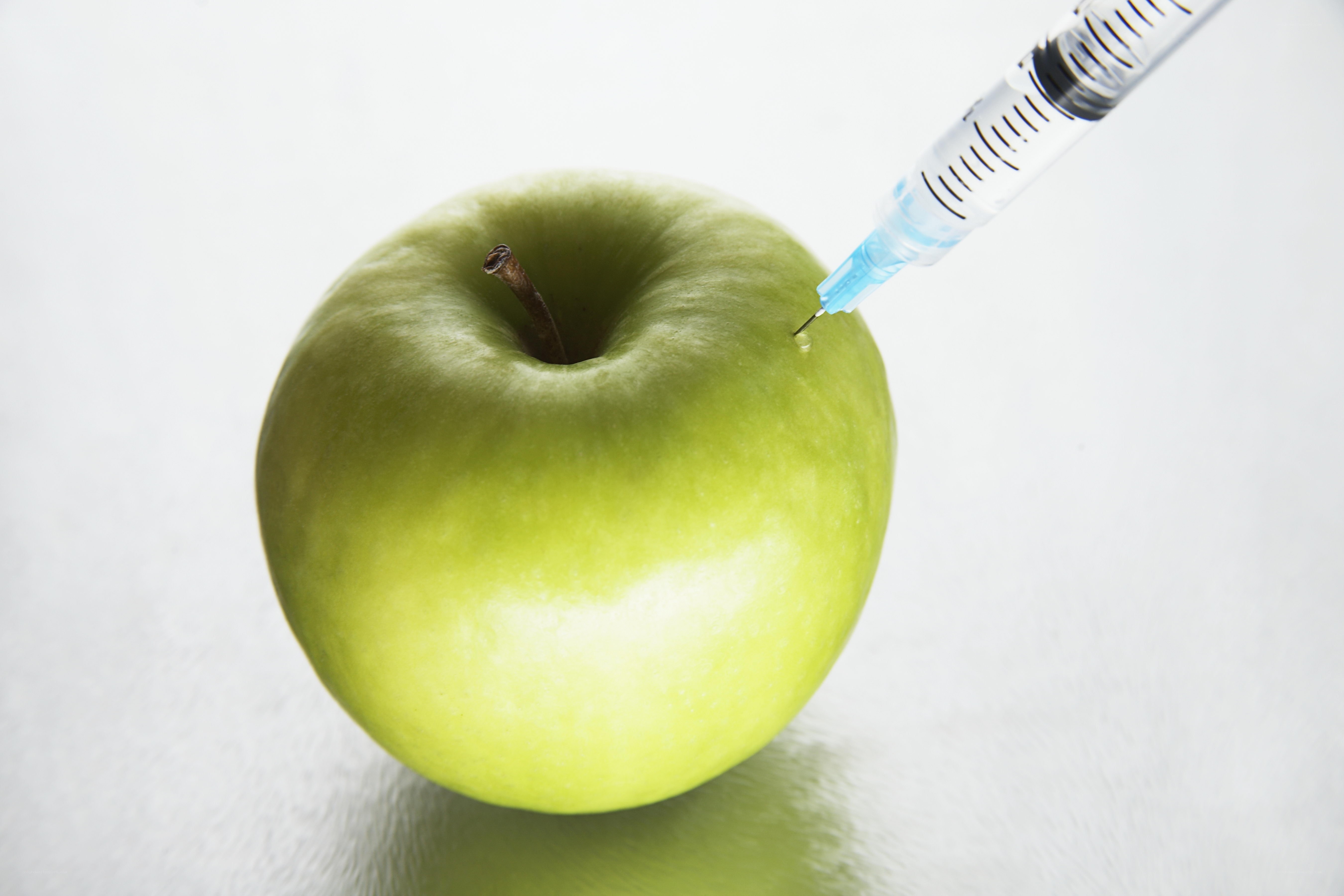 syringe injecting green apple