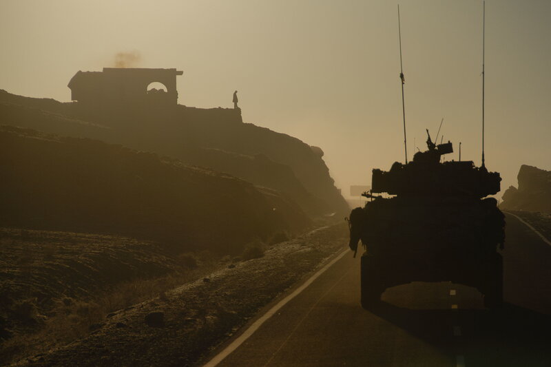 Tank on a desert road at sunset