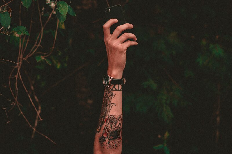 tattooed arm holding phone