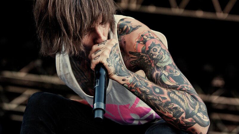 tattooed musician singing into microphone