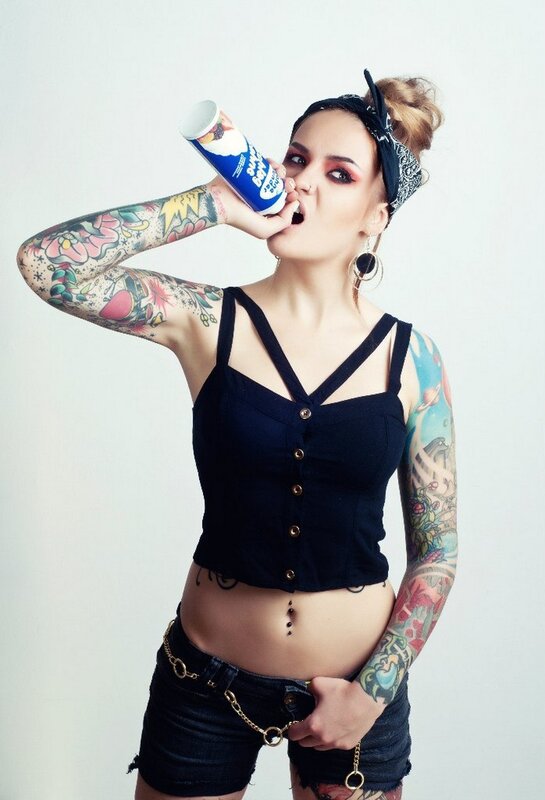 tattooed woman drinking from can