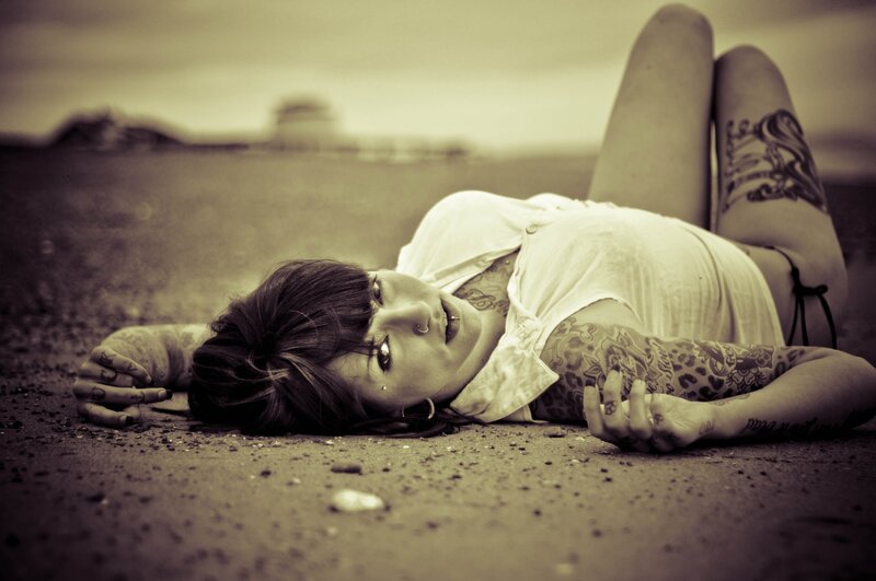 tattooed woman lying on ground