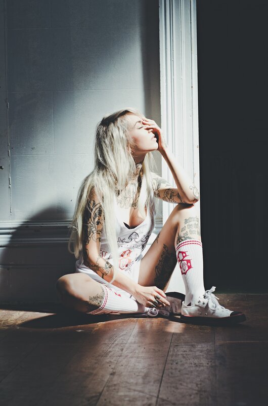 Tattooed Woman Sitting — White, Dramatic, Afternoon