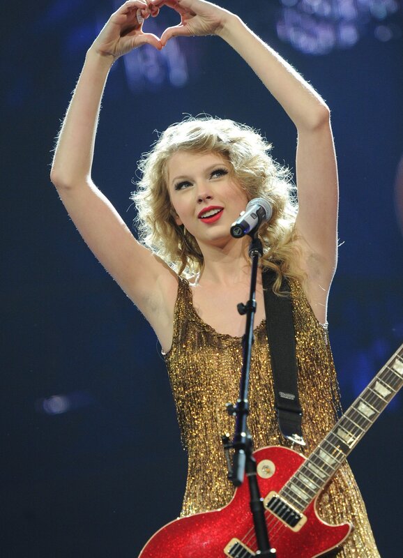 Taylor Swift on stage making a heart