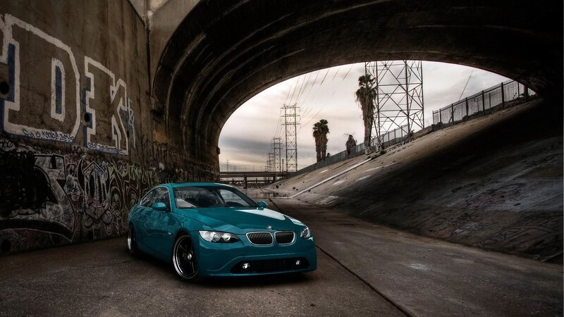 Teal BMW under a bridge
