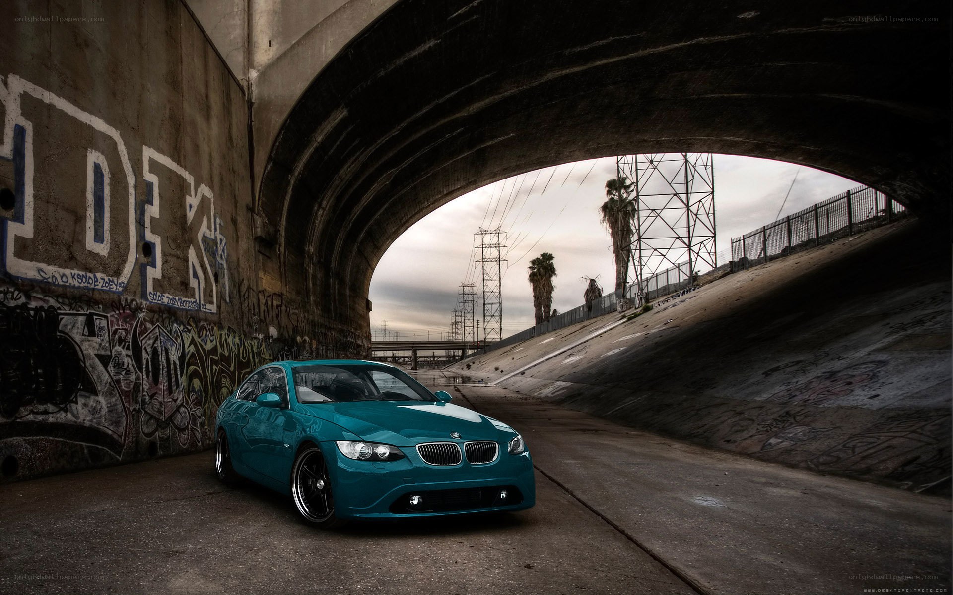 Teal car under concrete bridge
