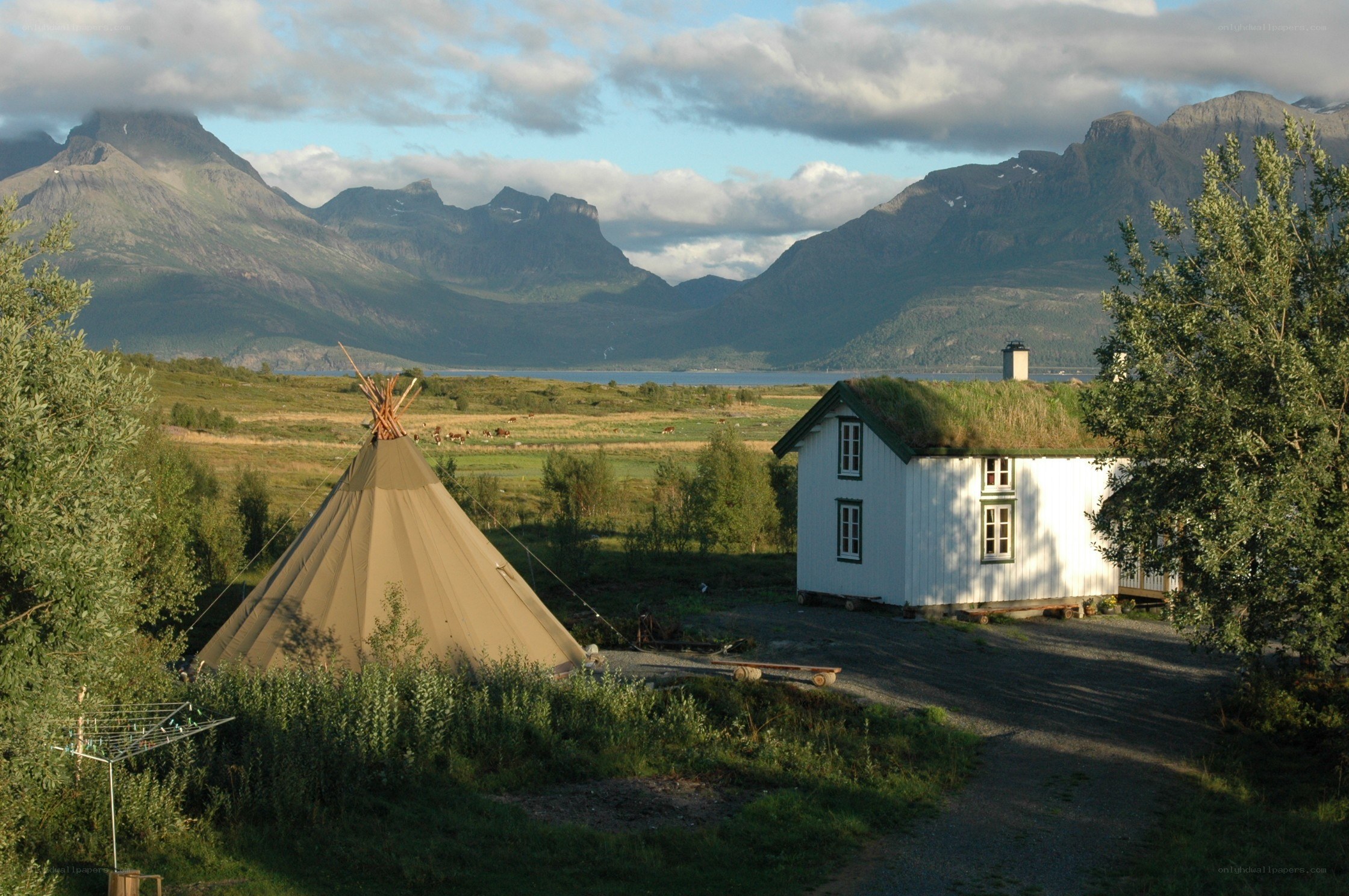 Teepee and cottage in mountain valley