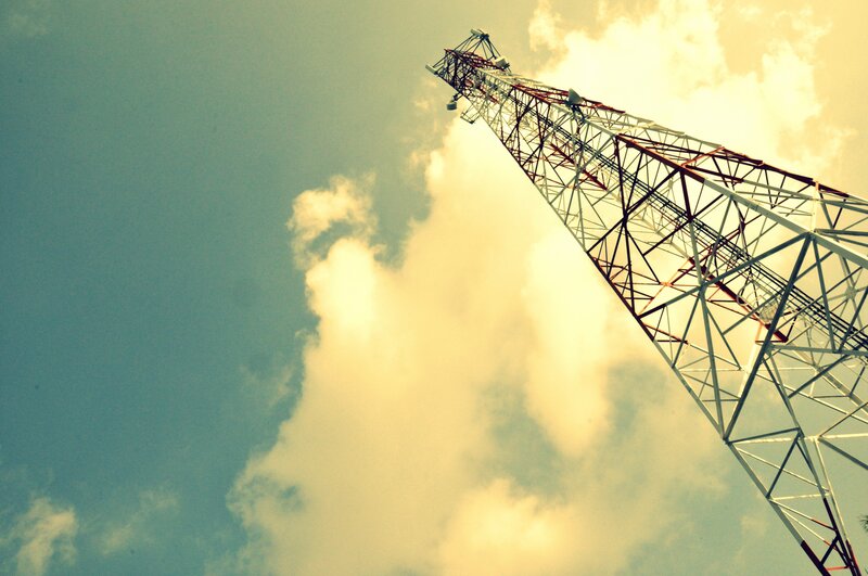 Telecom tower against cloudy sky