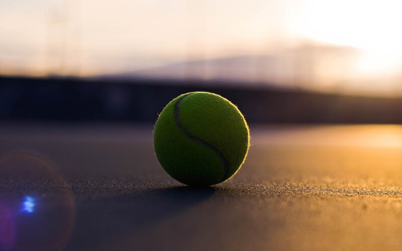 Tennis ball on court at sunset