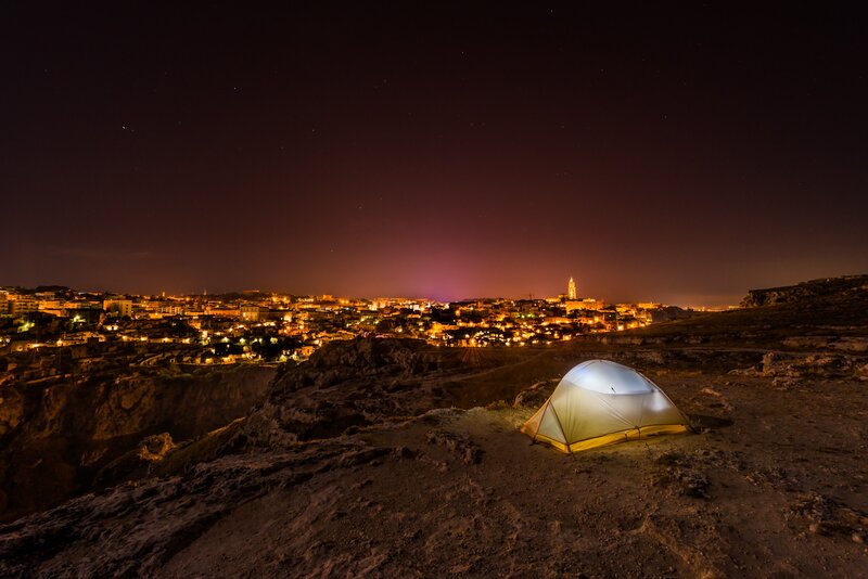 Tent on a cliff overlooking a city at night