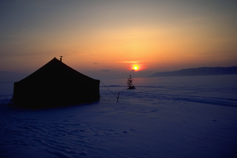 Tent on frozen lake at sunset