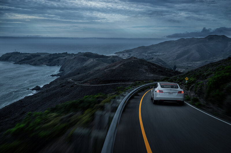 Tesla on coastal road at dusk