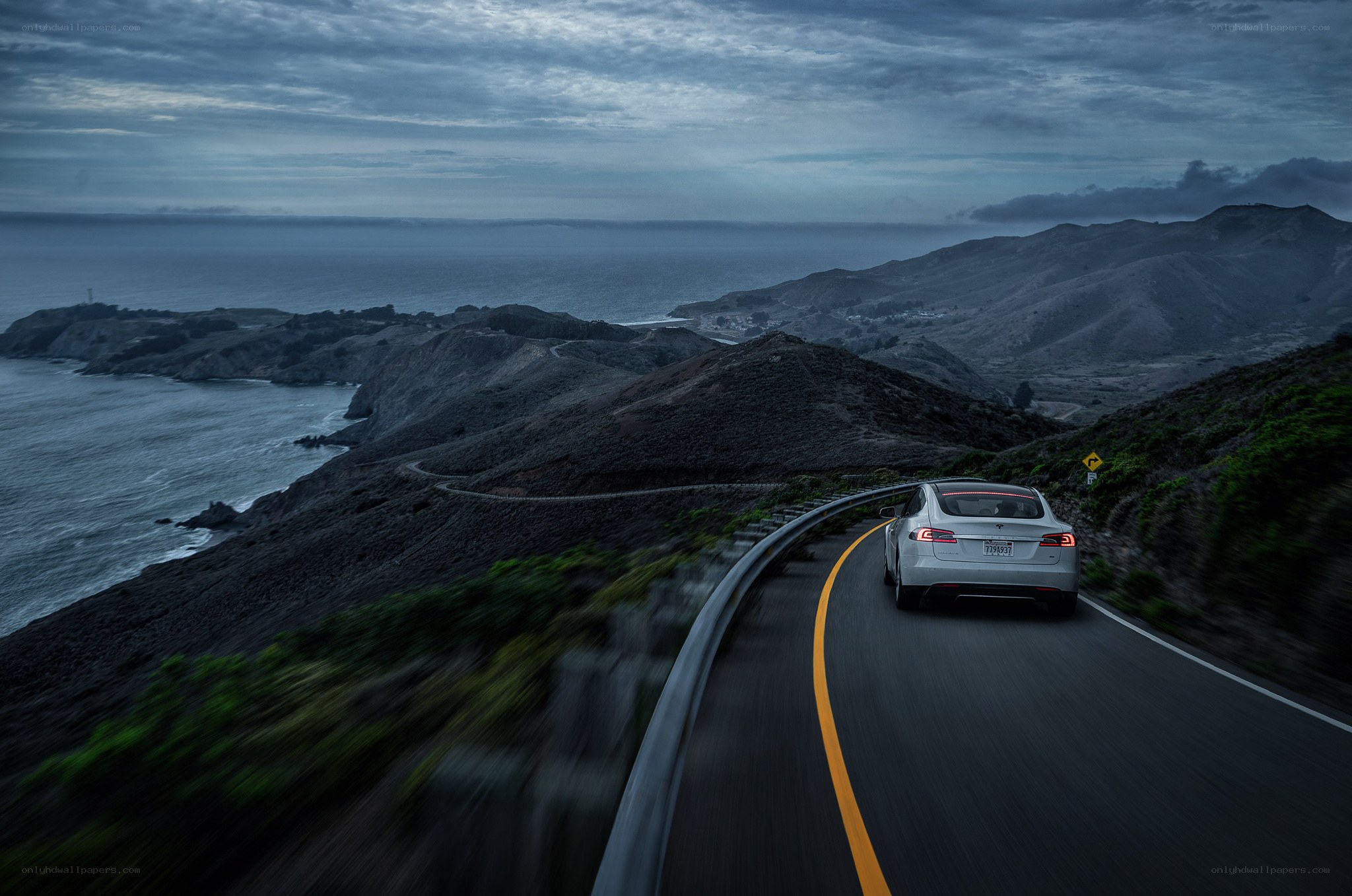 Tesla on coastal road at dusk