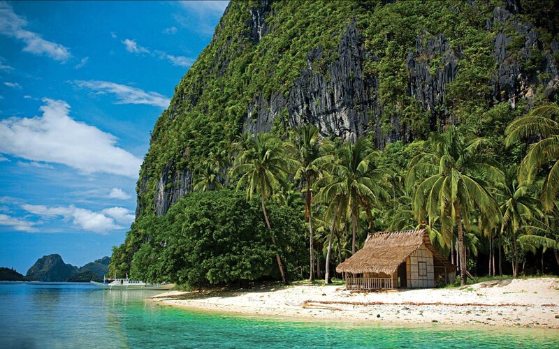 Thatched Hut on Beach — Blue, Serene, Afternoon, Photograph, Palm Trees, Cliff, Boat, Ocean