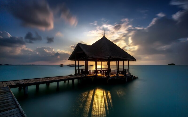 Thatched Pavilion on Pier — Blue, Serene, Sunset, Photograph, Ocean, Clouds