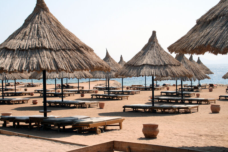Thatched Umbrellas on Beach — Brown