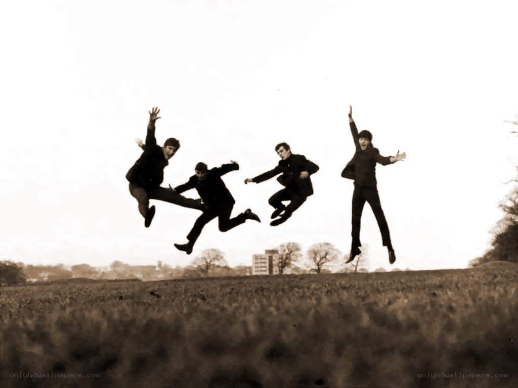 The Beatles jumping in a field