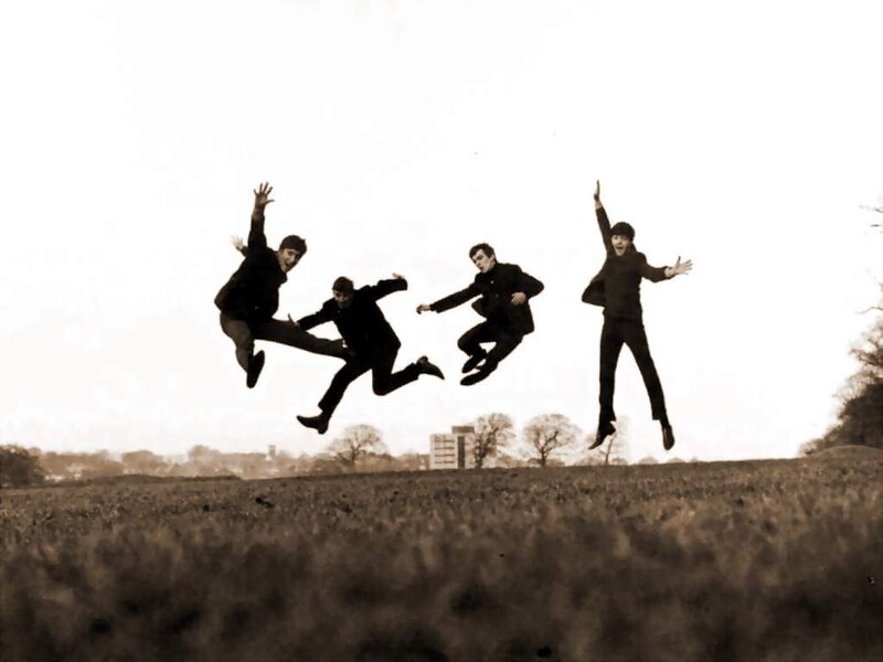 The Beatles jumping in a field