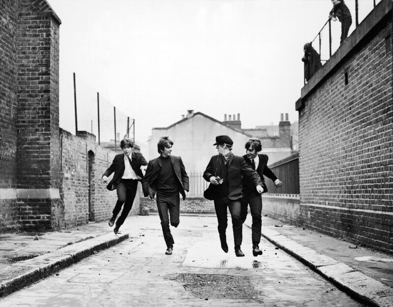 The Beatles running in an alley