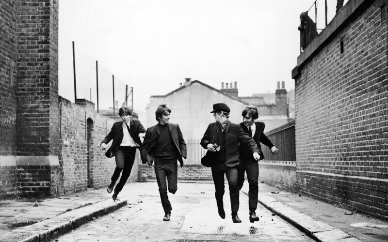 The Beatles running in an alley