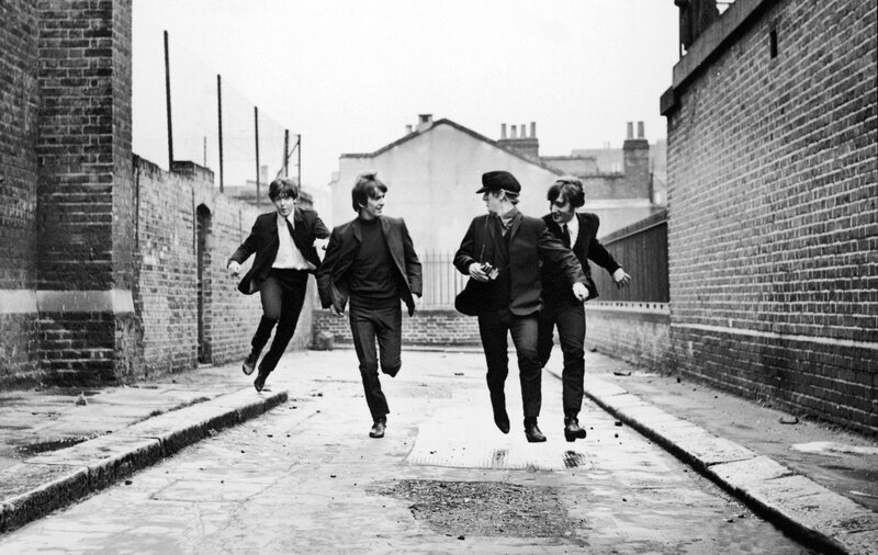 The Beatles running in an alley