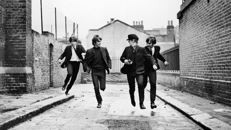 The Beatles running in an alley
