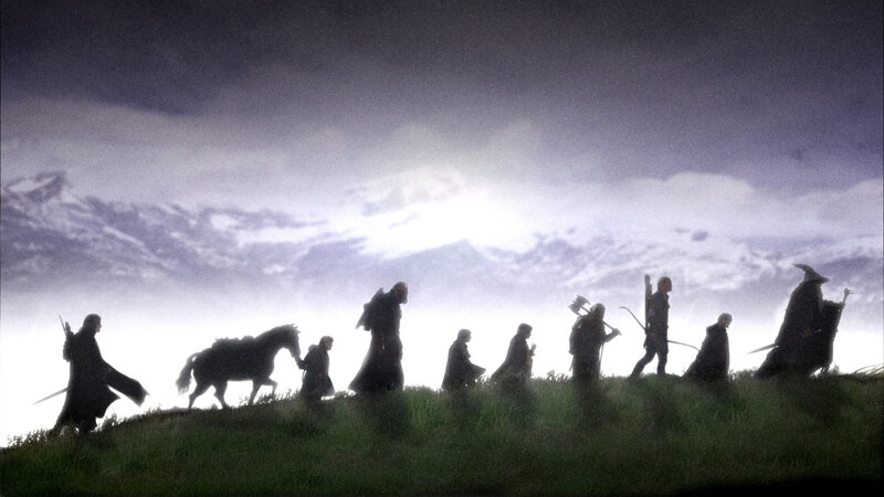 The Fellowship silhouetted on a hill
