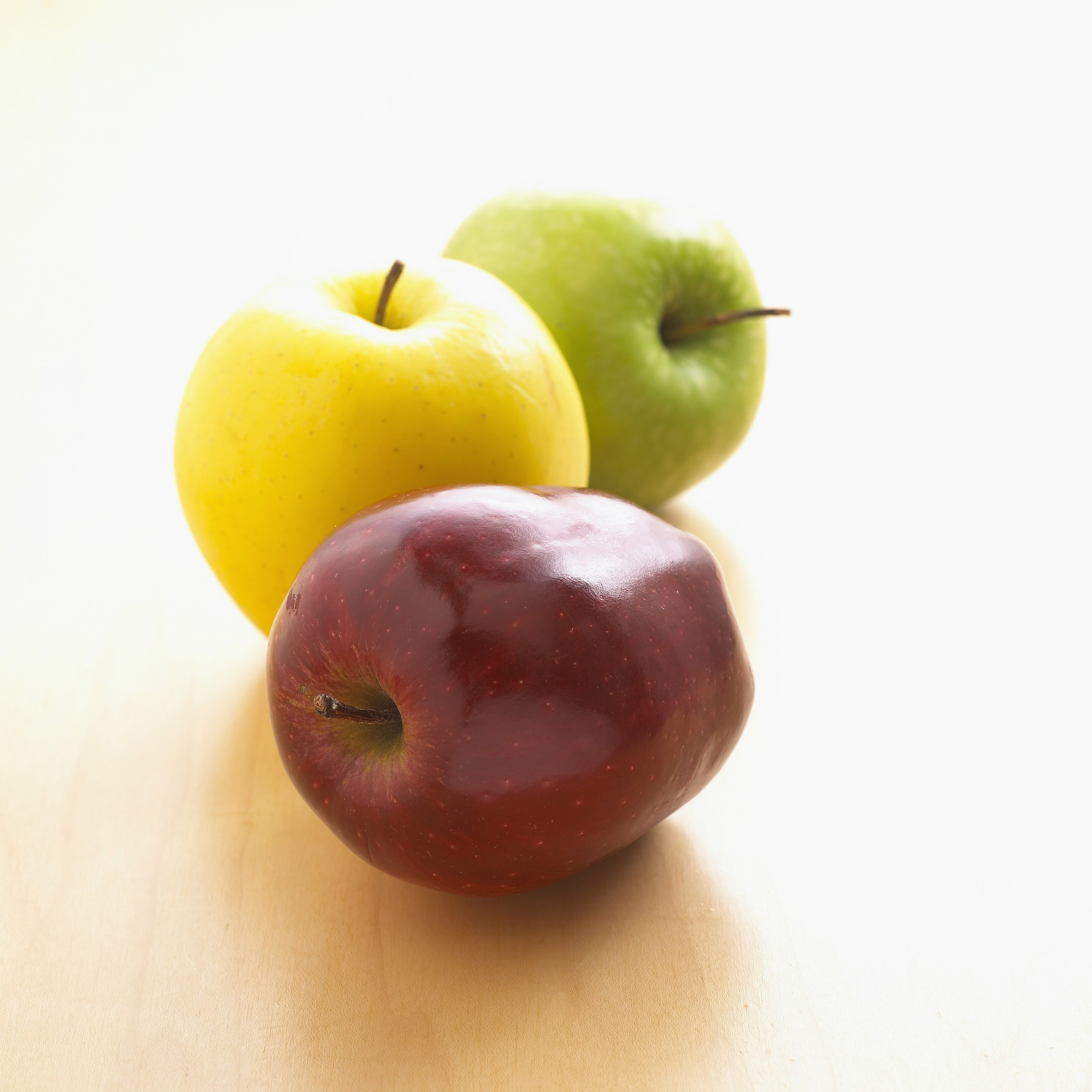 Three apples on a wooden surface