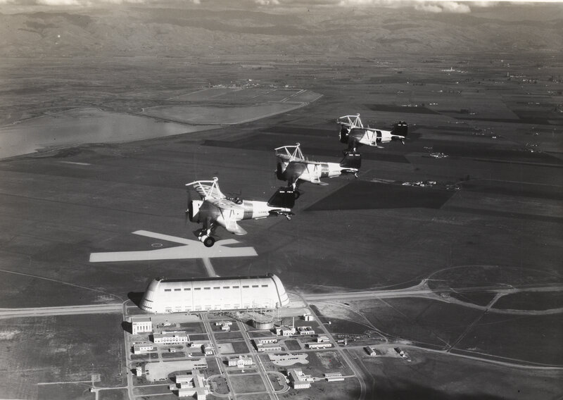 Three biplanes flying over airfield