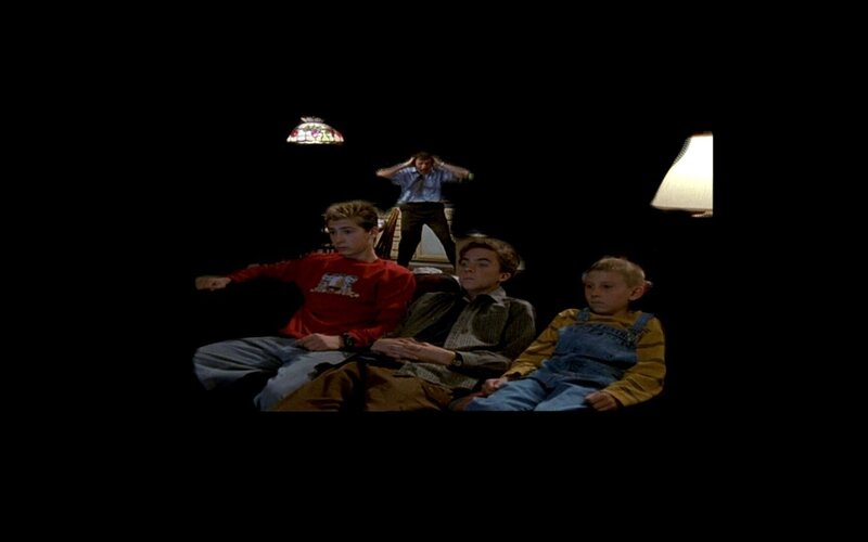 Three boys watching TV in a dark room