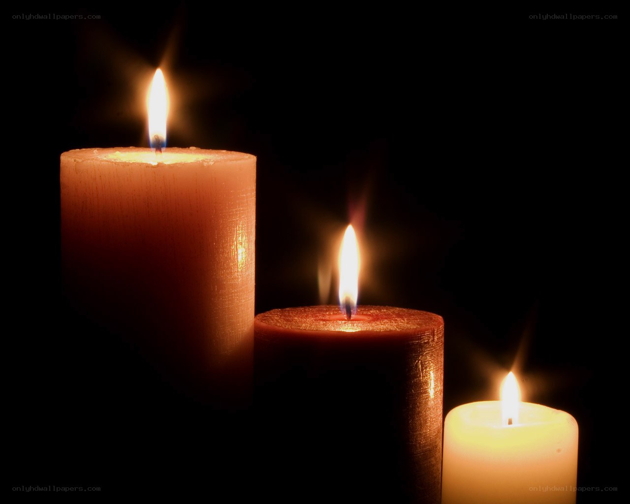 Three candles lit in darkness