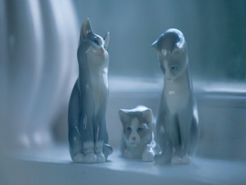 three cat figurines on a windowsill