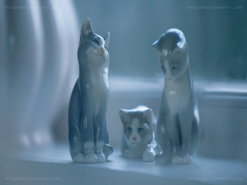 three cat figurines on a windowsill
