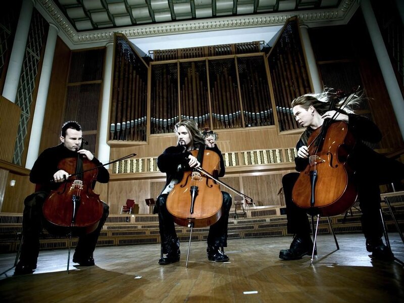 Three cellists performing in a concert hall
