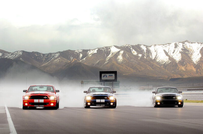 Three Ford Mustangs on a racetrack