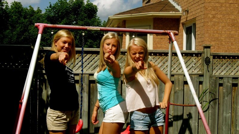 Three girls posing on a swing set